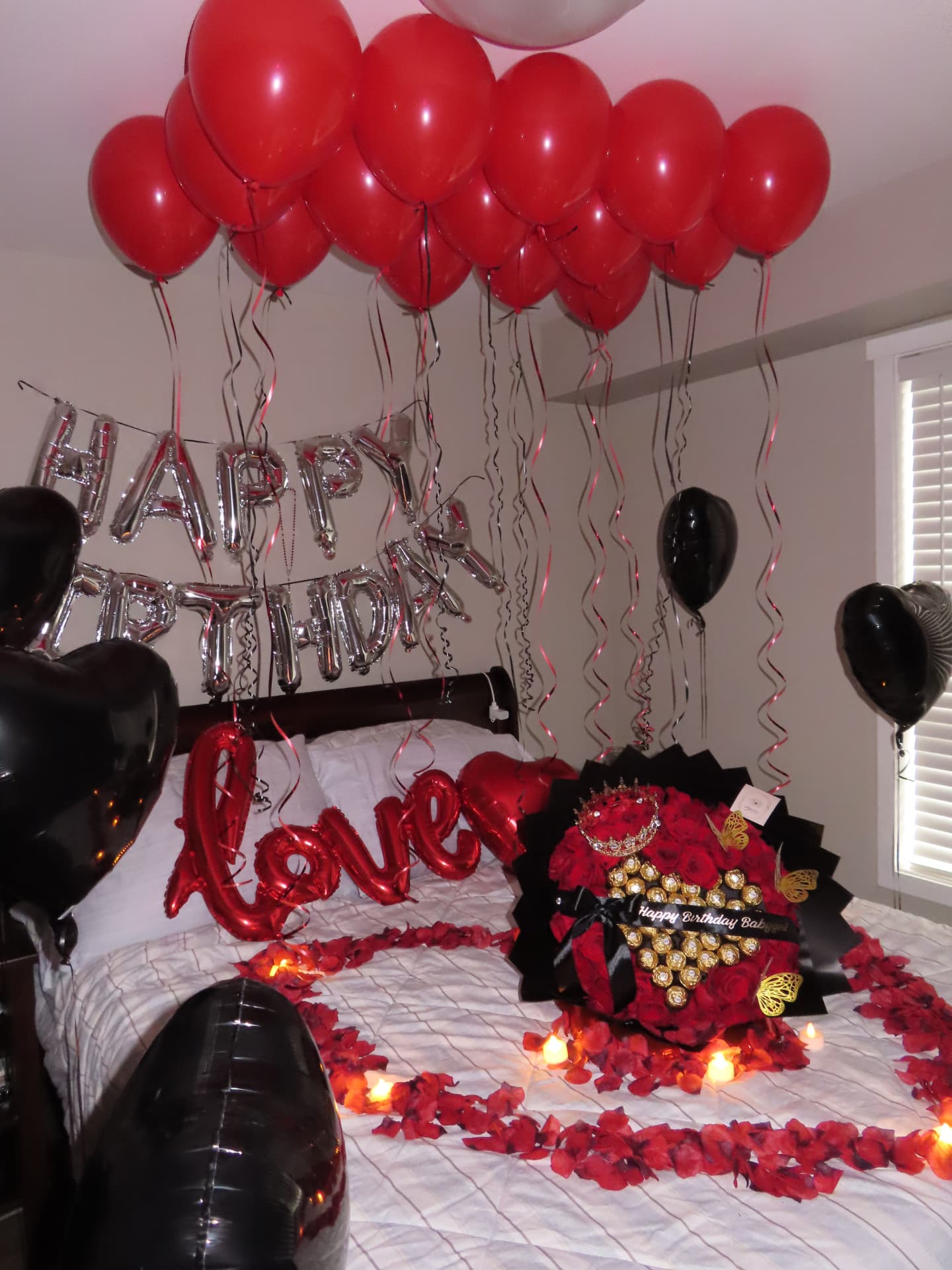 Birthday room setup with red balloons, silver lettering and a red rose box with chocolates